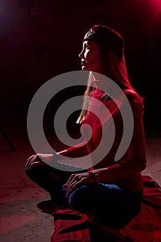 Portrait of a young beautiful woman in with long hair in a Tatar red hat and a red sweater. Fashion photo shoot in low key