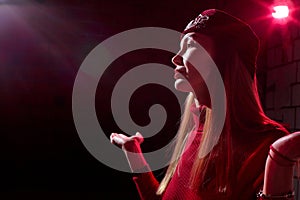 Portrait of a young beautiful woman in with long hair in a Tatar red hat and a red sweater. Fashion photo shoot in low key