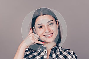 Portrait of young beautiful woman making a call me sign with her