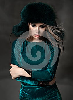 Portrait of young beautiful woman in new green fashion arctic fox winter fur ear flaps