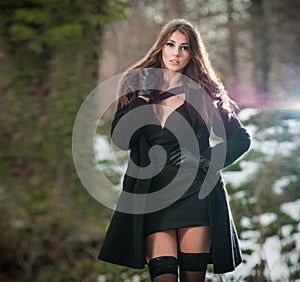 Portrait of young beautiful woman outdoor in winter scenery. Sensual brunette with long legs in black stockings posing fashionable