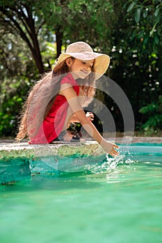 Portrait of young beautiful woman playing with water. Playful little girl in a park