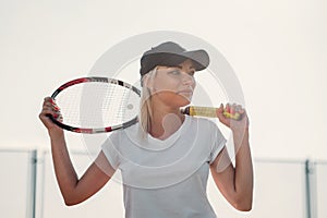 Portrait of young beautiful woman with racket for tennis on a court
