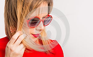 Portrait of a young beautiful woman with red sunglasses in studio.