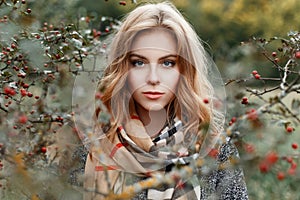 Portrait of young beautiful woman`s face with blue eyes in a fashionable gray coat in a vintage scarf