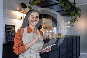 Portrait of young beautiful woman small business owner of coffee shop and cafe restaurant, Hispanic woman smiling and