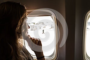 Portrait of young beautiful woman smiling and looking out from jetliner window indoors. photo