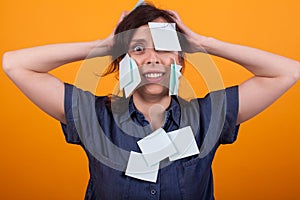 Portrait of young beautiful woman stressed with sticky notes on clothes and body standing over yellow background in