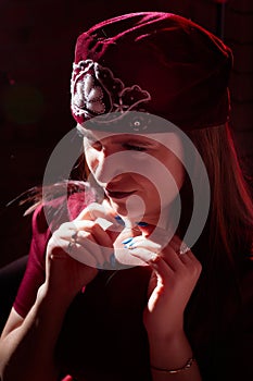 Portrait of a young beautiful woman in Tatar national folk red hat and a red dress. Fashion photo shoot in low key