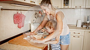 Portrait of young beautiful woman teaching her little child boy making cookies and baking pies on kitchen at home