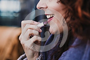 portrait of young beautiful woman using red lipstick outdoors in a terrace. Make up and lifestyle concept