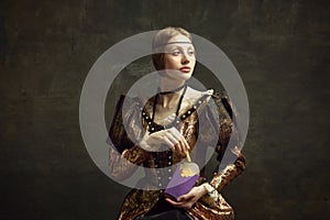 Portrait of young beautiful woman in vintage costume, eating fries against dark green background. Fast food lover