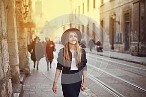 Portrait of young beautiful woman wearing hat walking in the old city. Street fashion concept. Toned