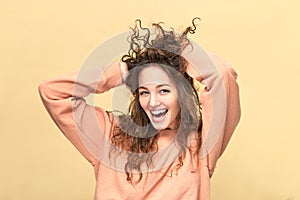 Portrait of a young beautiful woman wearing sweatshirt ruffling hair with her hands