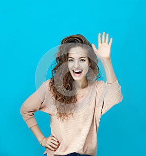 Portrait of a young beautiful woman wearing sweatshirt showing palm gesture hello and looking at you coquettishly
