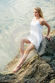 Portrait of young beautiful woman wearing white dress on the beach. Summer time, relaxation or vacations concept