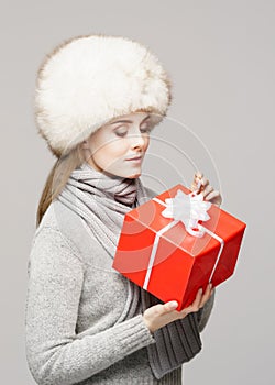 Portrait of a young and beautiful woman in a winter hat with Christmas present