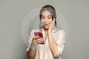 Portrait of young beautyful happy excited woman with phone. Surprised female model with smartphone