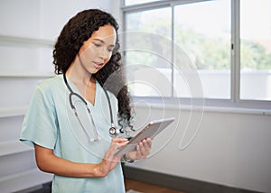Portrait of a young biracial female doctor, using digital tablet, eHealth