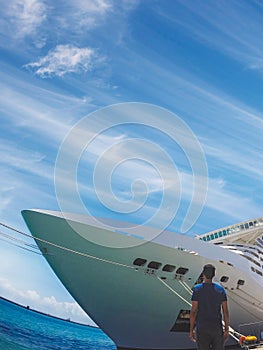Portrait of a young black male tourist in front of a cruise ship on cloudy sky. African tourist on the beach trip