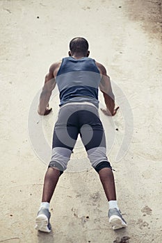 Portrait of a young black man doing push ups at the beach