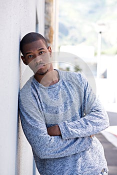 Portrait of young black man leaning against wall