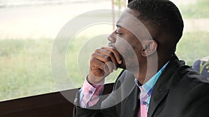 Portrait of young black man looks at window turns his head and looks at camera.