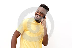 Young black man smiling and talking on mobile phone against white background