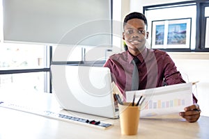 Portrait of a young black man using a laptop in a working environment, either an African businessman or a student