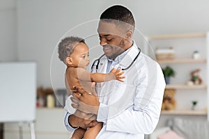 Portrait Of Young Black Pediatrician Holding Adorable Little Infant Boy In Hands