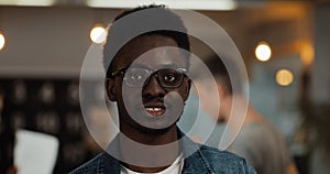 Portrait of young black smiling successful businessman wearing stylish glasses standing in modern office. Close up.