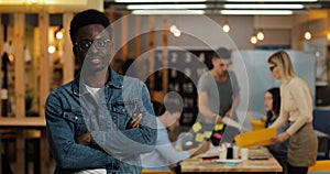 Portrait of young black smiling successful businessman wearing stylish glasses standing in modern office. Working people