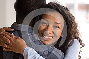 Portrait of young black smiling wife embracing husband