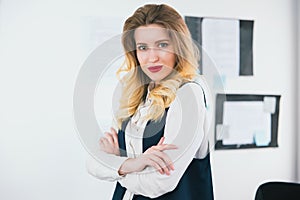 Portrait of young blond beautiful businesswoman wearing smart suit stands in her bright office, work concept