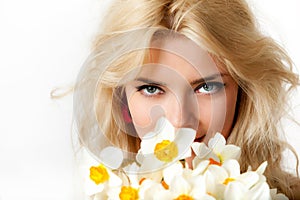 Portrait of young blond beautiful woman with green eyes in flowers