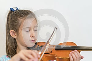 Portrait of a young blond teenage girl playing violin. Girl playing the violin on a light background