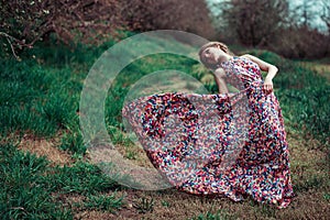 Portrait of a young blond woman on a background of spring trees. girl spinning. pink dress fluttering in the wind