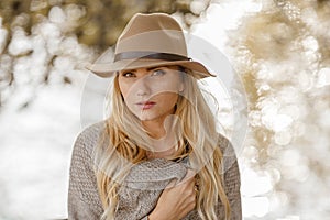 Portrait of a young blond woman with freckles wearing a hat in t