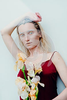 Portrait of the young blonde attractive woman with the fashion alien gold make up standing with the iris flowers