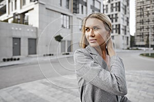 Portrait of young blonde businesswoman in gray suit walking in the city