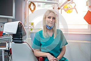Portrait of young blonde dentist woman sitting in her workplace in dental office.