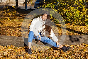 Portrait of a young blonde girl in stylish ripped jeans posing in an autumn park