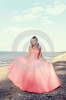 Young blonde woman at the beach with red tulle ball dress