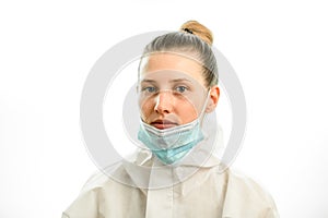 Portrait of young blonde woman with downcast medical mask on grey background