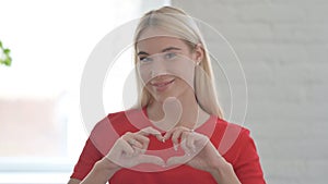 Portrait of Young Blonde Woman showing Heart Shape by Hands