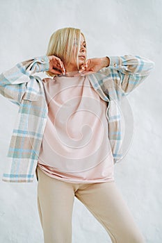 Portrait of young blonde woman in sportswear on background of white wall