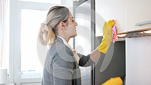 Portrait of young blonde woman washing cupboards on kitchen with cloth