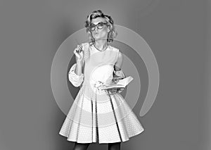 Portrait of young blonde woman wearing glasses hold book against blue background.