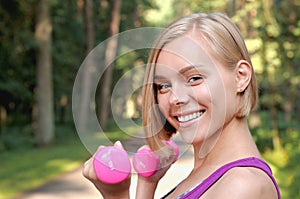 Portrait of young blonde woman working out with dumbbells