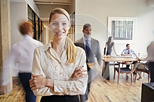 Portrait of young blonde woman in a busy modern workplace photo